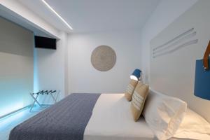 a white bedroom with a bed and a chair at Hostal Boutique La Mar Serena in Peniscola