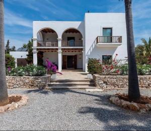 a white house with a palm tree in front of it at Villa Elena in Sant Josep de Sa Talaia