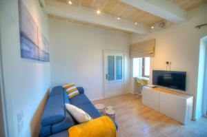 ein Wohnzimmer mit einem blauen Sofa und einem TV in der Unterkunft Comfy 1 bedroom - Sun terrace & sea views GBUH1-1 in Valletta