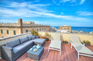 eine Terrasse mit einem Sofa und Stühlen auf dem Balkon in der Unterkunft Comfy 1 bedroom - Sun terrace & sea views GBUH1-1 in Valletta