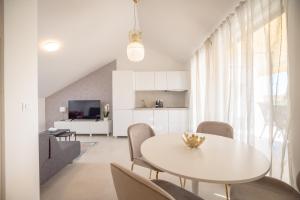 a white dining room with a white table and chairs at Apartments Mila in Sveti Filip i Jakov