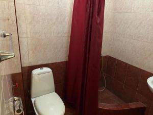 a bathroom with a toilet and a red shower curtain at Квартира студия на улице Цхалтубо in Tbilisi City