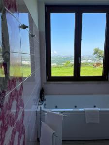 a bathroom with two windows and a bath tub with two white chairs at Mirabel in Chieti