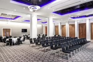 une salle de conférence avec des chaises, des tables et un écran de projection dans l'établissement Radisson Blu Hotel, Cardiff, à Cardiff