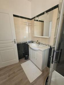 ein Badezimmer mit einem weißen Waschbecken und einem Spiegel in der Unterkunft Petit pavillon cosy avec extérieur in Mèze