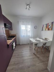eine Küche mit einem weißen Tisch und Stühlen in einem Zimmer in der Unterkunft Petit pavillon cosy avec extérieur in Mèze