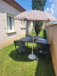 einen Tisch mit einem Regenschirm im Gras in der Unterkunft Petit pavillon cosy avec extérieur in Mèze