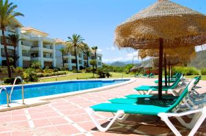 grupa krzeseł i parasol obok basenu w obiekcie Beautiful luxurious 2 bedroom apartment with a breathtaking view at La Cala Golf w mieście La Cala de Mijas