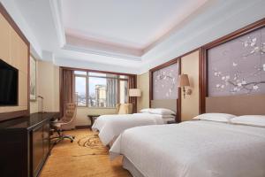 a hotel room with two beds and a flat screen tv at Sheraton Shantou Hotel in Shantou