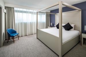 a bedroom with a canopy bed and a blue chair at Mercure Manchester Piccadilly Hotel in Manchester