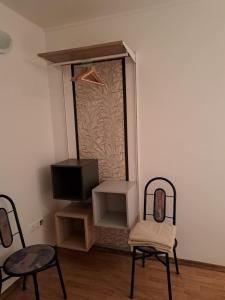 Zimmer mit 2 Stühlen, einem TV und einem Spiegel in der Unterkunft Nefelejcs Vendégház in Balatonkenese