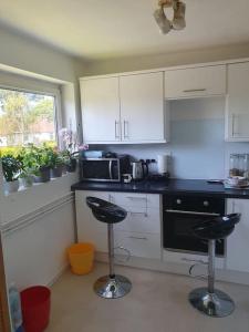 a kitchen with two bar stools in front of a stove at 1bedroom flat wt ext sofa chair in Horsham