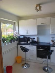 a kitchen with two bar stools and a microwave at 1bedroom flat wt ext sofa chair in Horsham