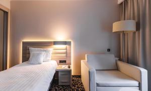 een hotelkamer met een bed en een stoel bij Antonińska Resort SPA in Boszkowo