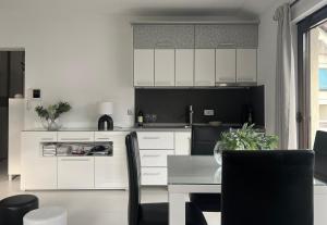 una cocina con armarios blancos y una mesa con sillas. en Apartments Villa Stefan, en Budva