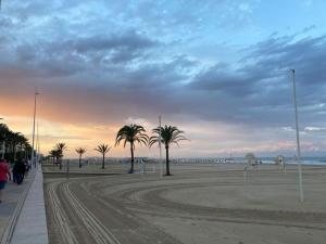 a beach with palm trees and the ocean at sunset at Apartament Bari Playa in Playa de Gandia