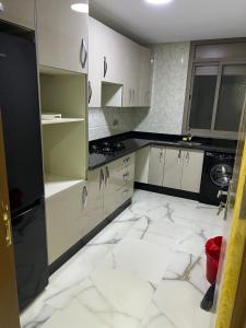 eine Küche mit weißem Marmorboden und weißen Schränken in der Unterkunft Apartment Nador Jadid Hay Al Matar Appart 009 in Nador