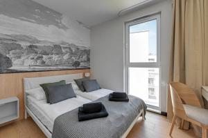 een slaapkamer met 2 bedden en een groot raam bij Luxury Aura 40 - 6 by Grand Apartments in Gdańsk