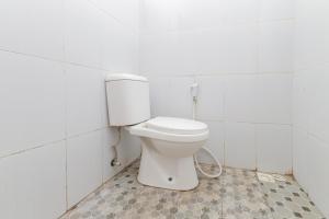 a bathroom with a toilet in a white tiled room at RedDoorz at WR Supratman Batu in Batu