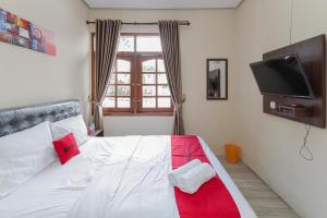 1 dormitorio con 1 cama con colcha roja y blanca en RedDoorz at WR Supratman Batu en Batu