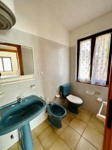 y baño con lavabo azul y aseo. en I bilocali di via Ginestre, Rena Majore, en Rena Majore