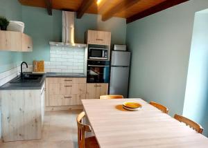una cocina con mesa de madera y sillas. en Gîtes Le Lilas - Lac de Pareloup en Canet-de-Salars
