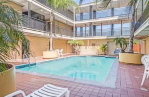 une grande piscine avec des chaises et un bâtiment dans l'établissement Super 8 by Wyndham New Orleans, à La Nouvelle-Orléans