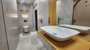 Baño blanco con lavabo y espejo en Hotel Nova Bling, en Rajkot