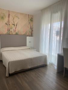 a bedroom with a bed and a large window at Hotel Columbia & Ninfea in Lido di Jesolo