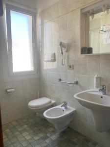 La salle de bains est pourvue de toilettes et d'un lavabo. dans l'établissement Hotel Columbia & Ninfea, à Lido di Jesolo