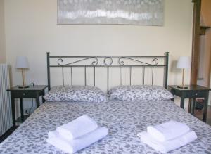 a bed with two white towels on it with two tables at Casa Liberty - WelcHome in Cannobio