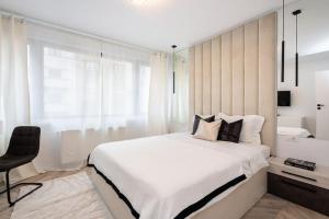 a white bedroom with a large bed and a chair at Mellow - Calea Victoriei - 2BR Luxury Apartment in Bucharest