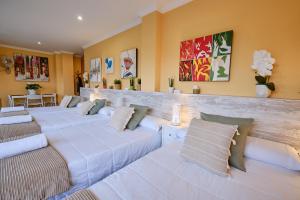 a room with four white beds with pillows at Peregrina Pensión 1 in O Pedrouzo