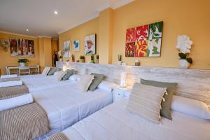 una habitación con cuatro camas blancas con almohadas en Peregrina Pensión 1, en O Pedrouzo