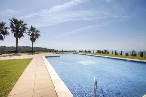 a large swimming pool with palm trees in the background at LETS HOLIDAYS Luxury house in Cala Llevado in Tossa de Mar