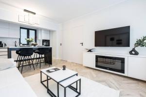 a white living room with a white couch and a tv at Mellow - Calea Victoriei - 2BR Luxury Apartment in Bucharest