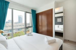 a bedroom with a white bed and a large window at Fairways West Tower - 1BR Apartment - Allsopp&Allsopp in Dubai