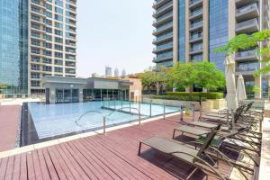 a deck with chairs and a swimming pool with buildings at Fairways West Tower - 1BR Apartment - Allsopp&Allsopp in Dubai