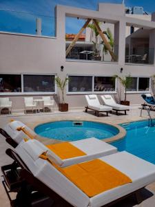 een zwembad met ligstoelen en een huis bij Porto Greco Village Beach Hotel in Chersonissos