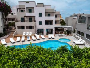 an apartment with a swimming pool and lounge chairs and a building at Porto Greco Village Beach Hotel in Hersonissos