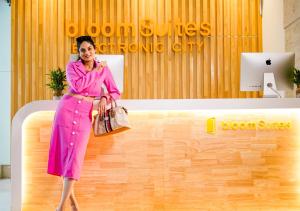 BloomSuites I Electronics City في بانغالور: امرأة ترتدي ثوب وردي تجلس على مقعد