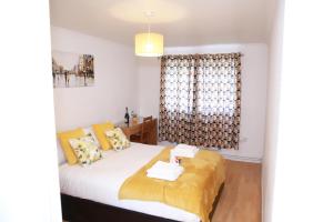 a bedroom with a bed with yellow pillows and a window at Kenton Cozy Apartment in Harrow