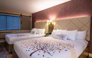 Una habitación de hotel con 2 camas con hojas. en Empeiria High Sierra Hotel, en Mammoth Lakes