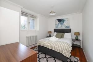 a white bedroom with a bed and a window at Bright & modern Islington 2BD apt for 6 in London