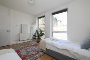 a bedroom with two beds and a large window at Stay in Islington in style 3BDR apt Nr Upper St in London