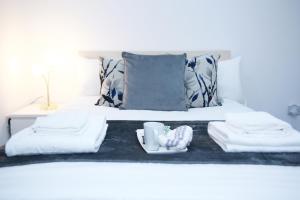 een bed met twee handdoeken en een dienblad met een kopje bij South Harrow Apartment in Londen