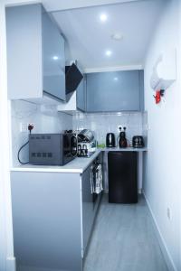 a small kitchen with blue cabinets and a microwave at South Harrow Apartment in London