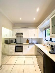 a large white kitchen with white cabinets and appliances at DE WET 5 FRANSCHHOEK in Franschhoek
