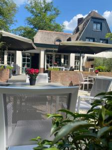 een patio met een tafel en stoelen en een huis bij Huize Hölterhof Wellness Hotel Restaurant in Enschede