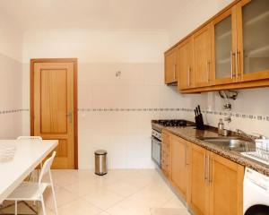 cocina con armarios de madera y encimera blanca en Harbour's way, spacious and cosy apartment, with AC, en Olhão